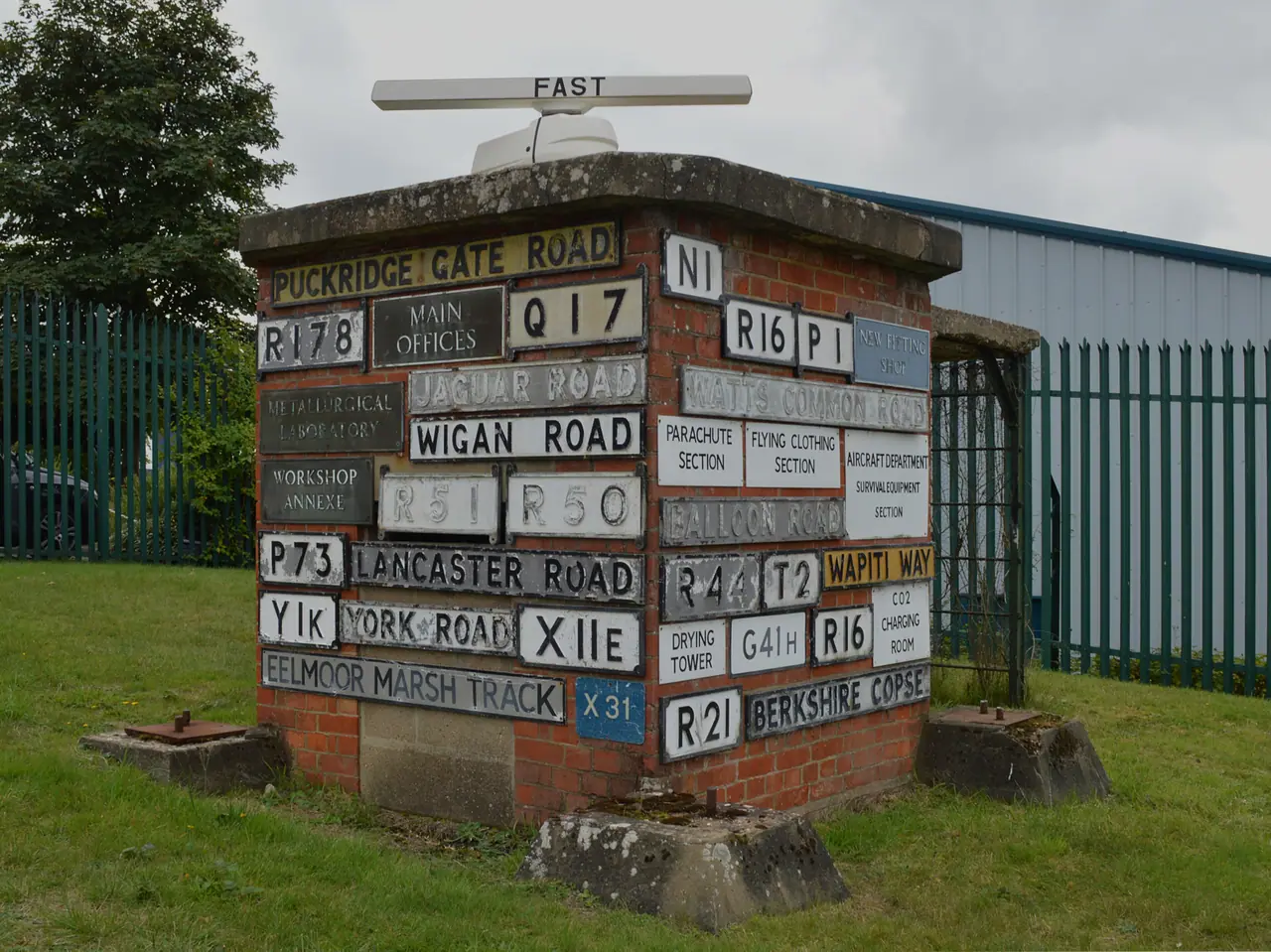A small brick building covered in old enamel road and building signs from the Royal Aircraft Establishment, outside the Farnborough Air Sciences Trust museum