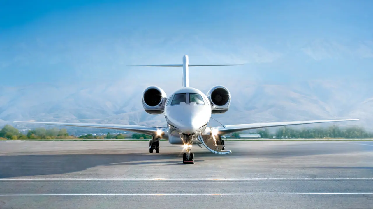 Private jet facing the camera on the apron, its airstair lowered, with mountains behind