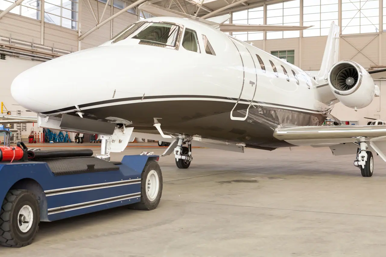 A private jet attached to its tug in a hangar