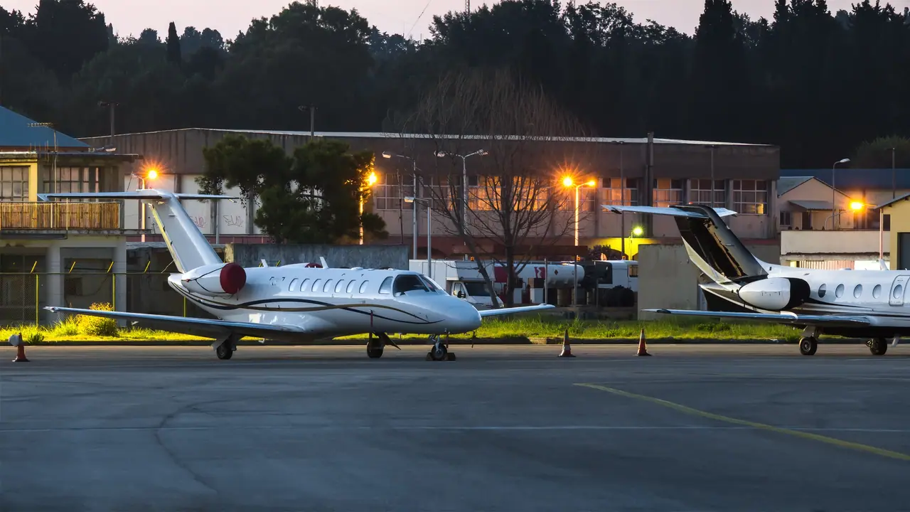 Private jets parked outside a business aviation terminal at dusk